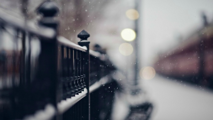 Snow falling on a fence with bokeh lights