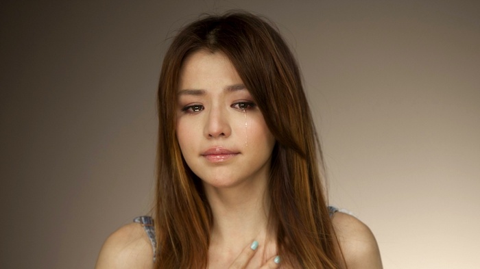 Asian woman crying with a tear on her cheek