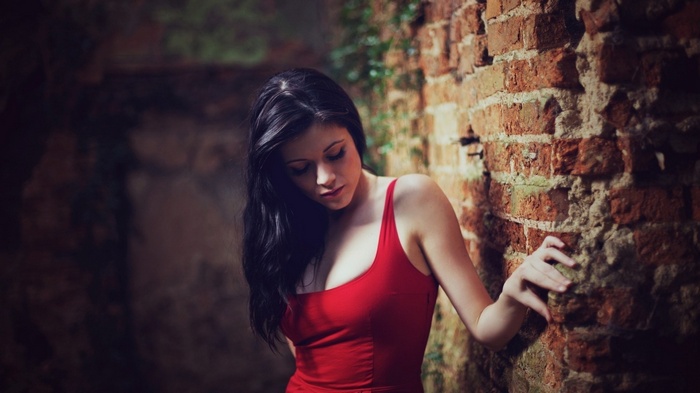 Samantha Laura Kaye in a red dress by a brick wall