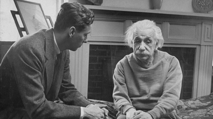 Albert Einstein and a man sitting indoors