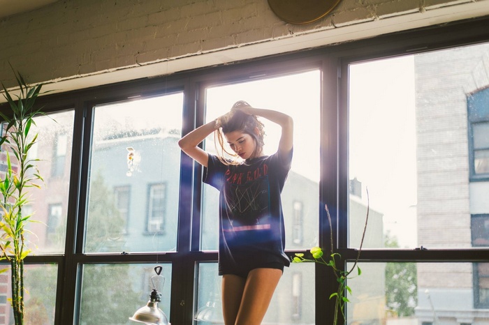 Woman with hands in hair in front of window