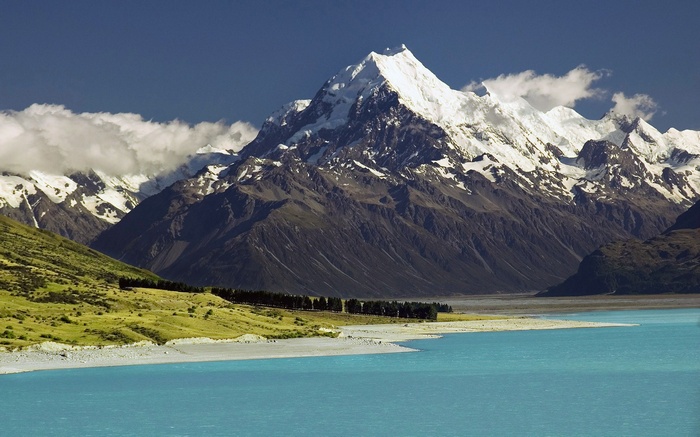 Snow-capped mountains rise above a turquoise lake