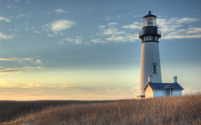 Lighthouse on a grassy hill at sunset