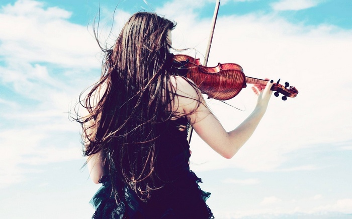 Woman playing violin against a blue sky