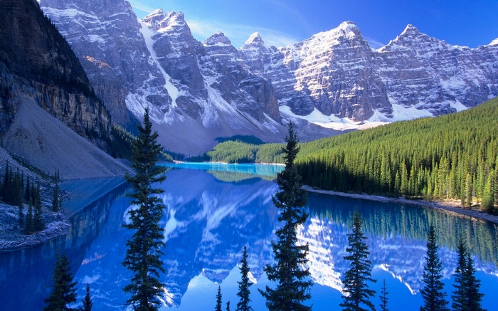 Moraine Lake with snow-capped mountains and pine forest