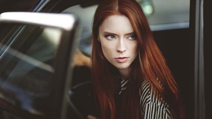 Redhead woman with long hair in a car