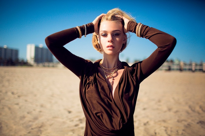 Nicola Peltz with hands on head on a beach