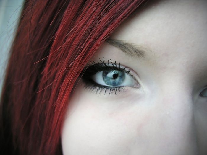 Close-up of a woman's blue eye and red hair