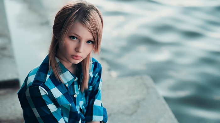 Young woman with blonde hair and blue eyes by the water