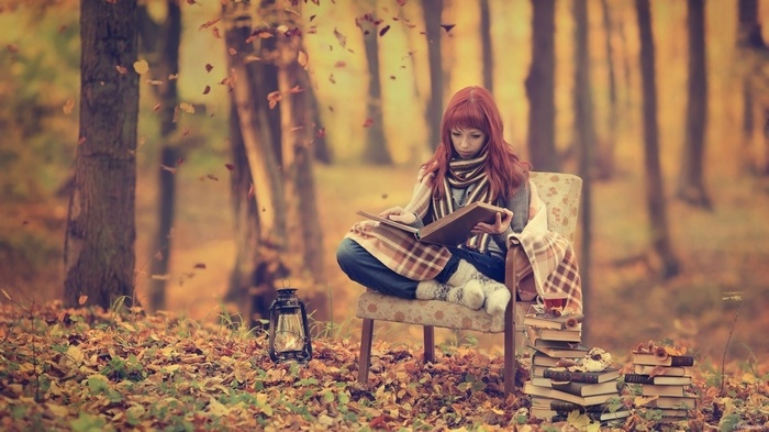 Woman reading a book in an autumn forest