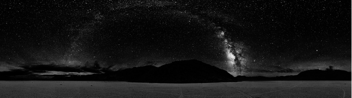 Monochrome panorama of the Milky Way over mountains