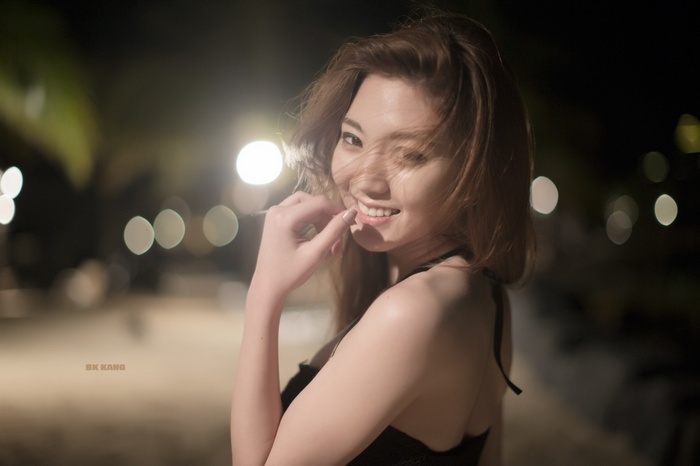 Asian woman smiling at night with bokeh lights