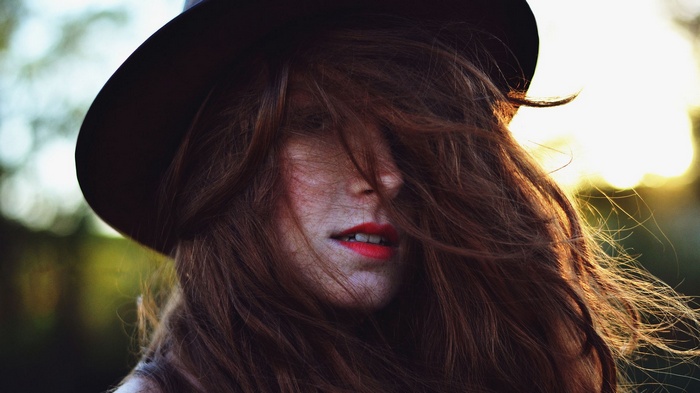 Woman with brown hair and hat in sunlight