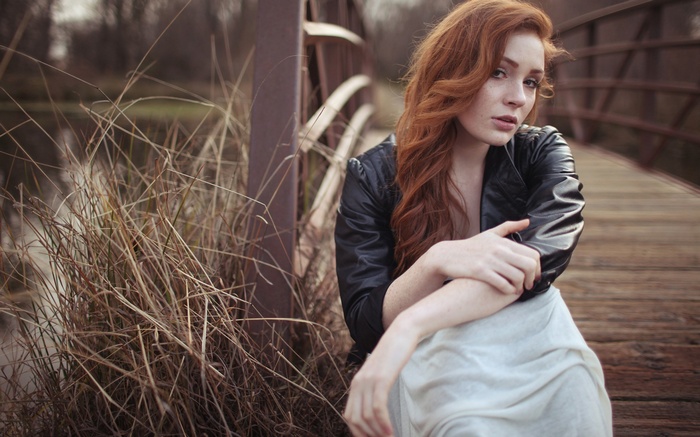 Redhead woman sitting on a wooden bridge