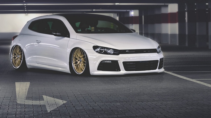 White Volkswagen Scirocco with gold rims in parking garage