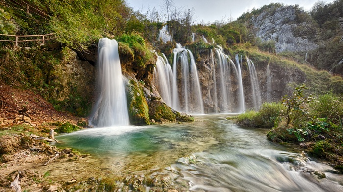 A cascading waterfall flows into a clear pool