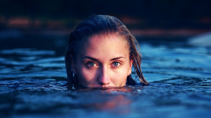 Woman with blue eyes emerging from dark water
