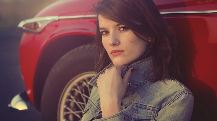 Woman leaning against a red vintage car