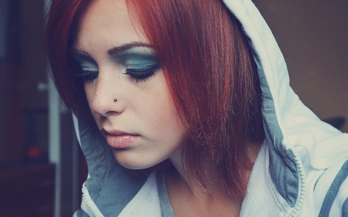 Woman with red hair and nose piercing wearing a hoodie
