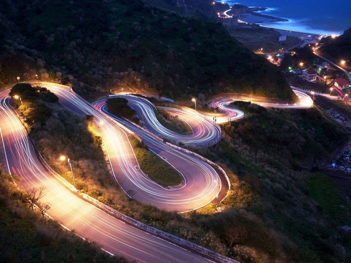 Nighttime view of winding mountain road with light trails