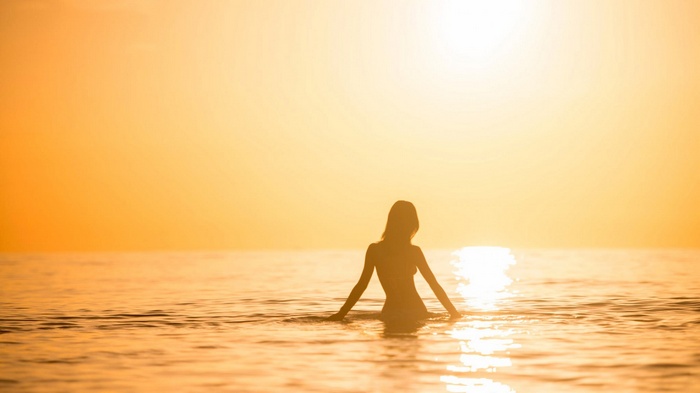 Woman in the sea at sunset silhouette