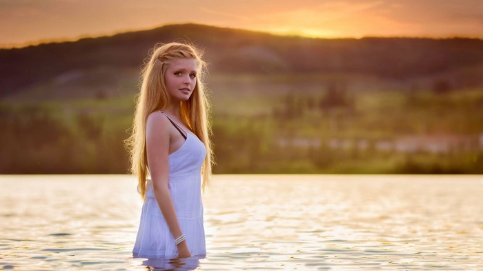 Woman with long blonde hair in a white dress in water