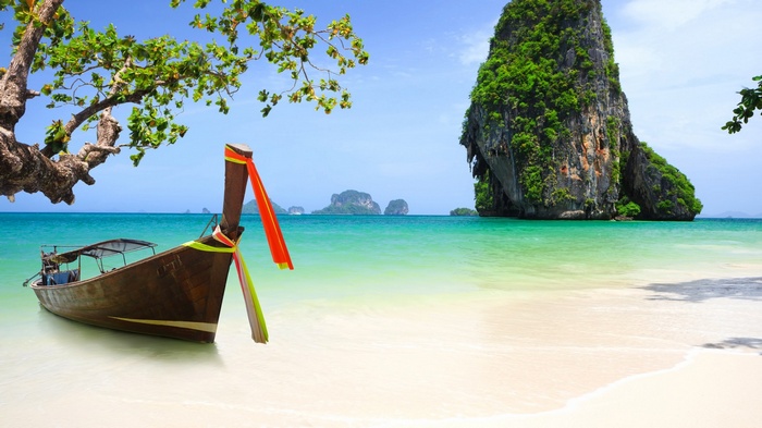 Longtail boat on a tropical beach with limestone karsts
