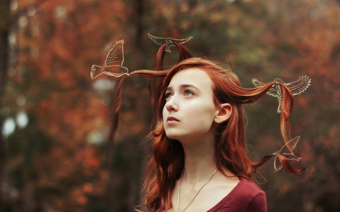 Redhead woman with birds in her hair in a forest