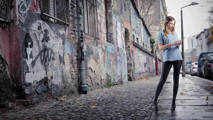 Woman looking at her phone on a graffiti-covered street