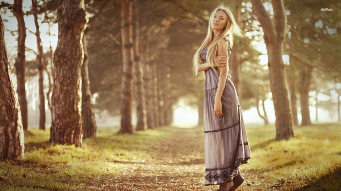 Blonde woman in a dress walking in a forest