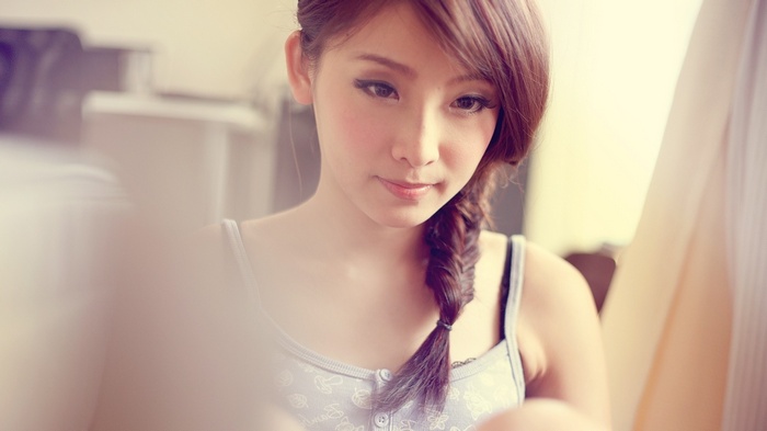 Asian woman with braided hair looking down
