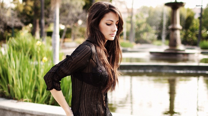 Woman with long brown hair wearing a sheer black shirt