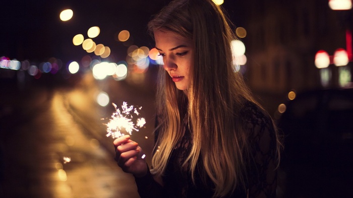 Woman holding a sparkler at night