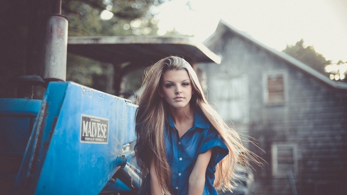 Woman in blue shirt next to a blue tractor
