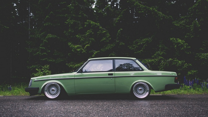 Green Volvo 240 coupe parked on a wet road