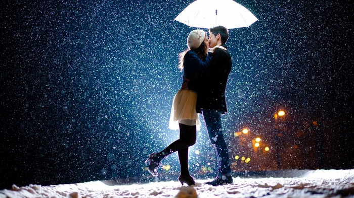 Couple kissing under an umbrella in the snow