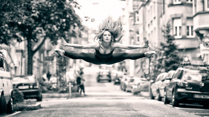 Woman performing a split jump in a city street