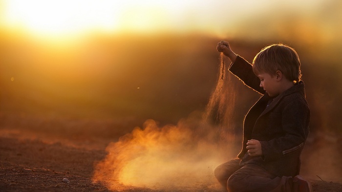 Boy playing with sand at sunset