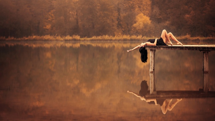Woman lying on a pier over a lake