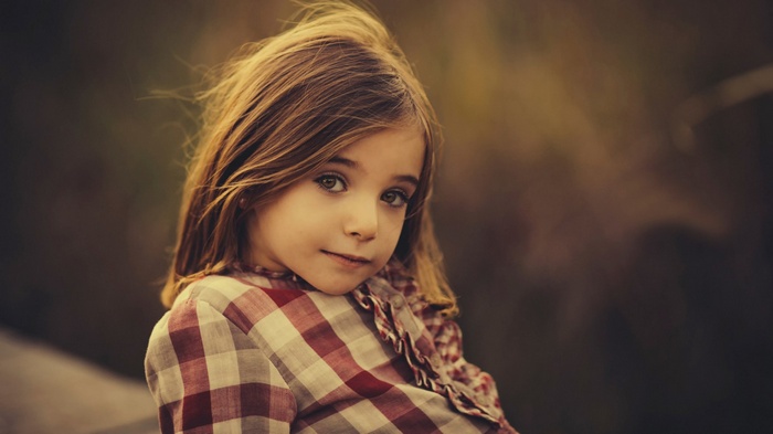 A young girl with brown hair wearing a plaid shirt