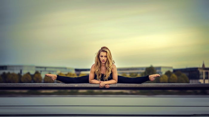 Blonde woman doing a split outdoors