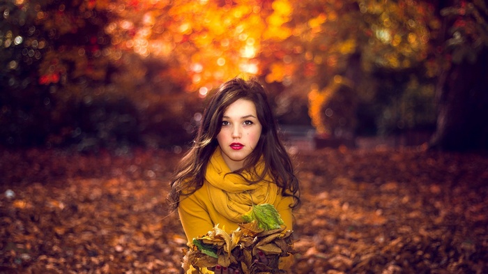 Woman in yellow scarf holding autumn leaves