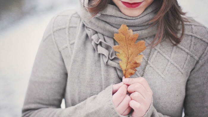 Woman in sweater holding an autumn leaf