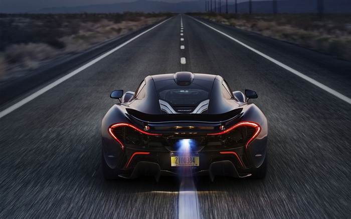Black McLaren P1 driving on a desert road at night