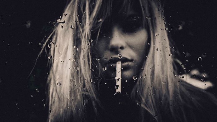 Woman smoking cigarette through raindrops