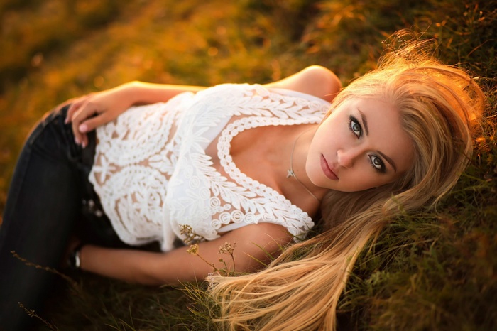 Blonde woman lying in grass at sunset