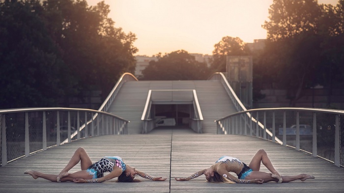 Two women in leotards on a bridge at sunset