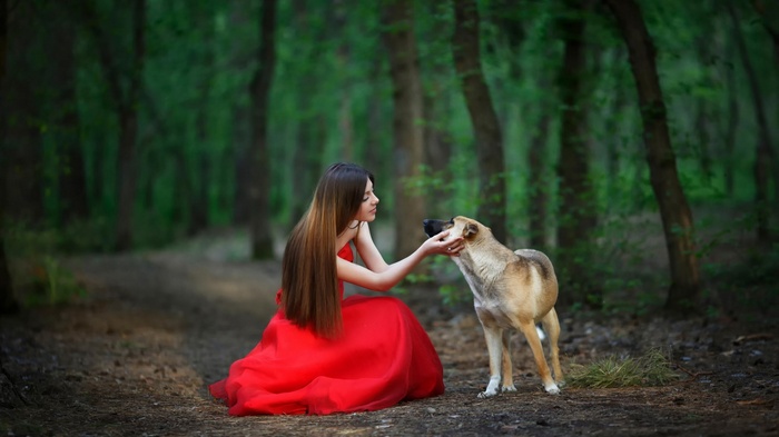Woman in red dress with dog in forest