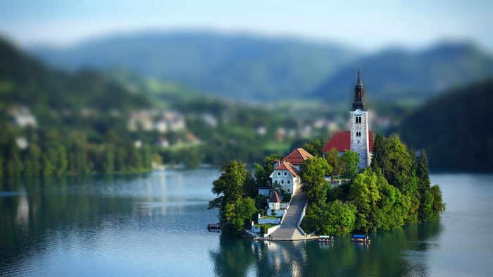 Church on an island in Lake Bled with mountains