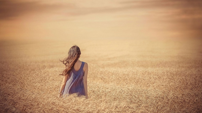 Woman in a blue dress in a wheat field
